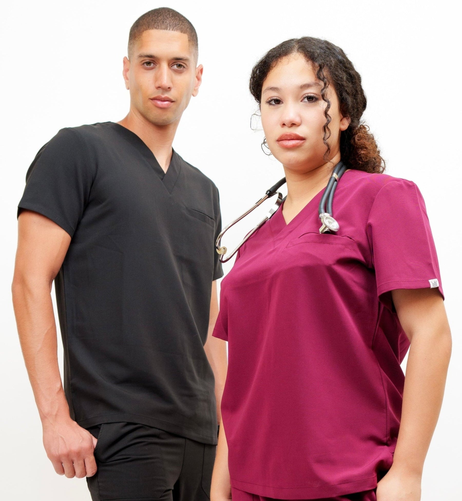 Two individuals wearing black and magenta medical scrubs on a white background
